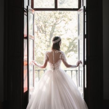 bride in wedding dress standing by window